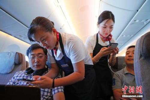 資料圖：乘務(wù)員們在客艙內(nèi)為旅客調(diào)試機(jī)上上網(wǎng)功能。<a target='_blank' ><p  align=